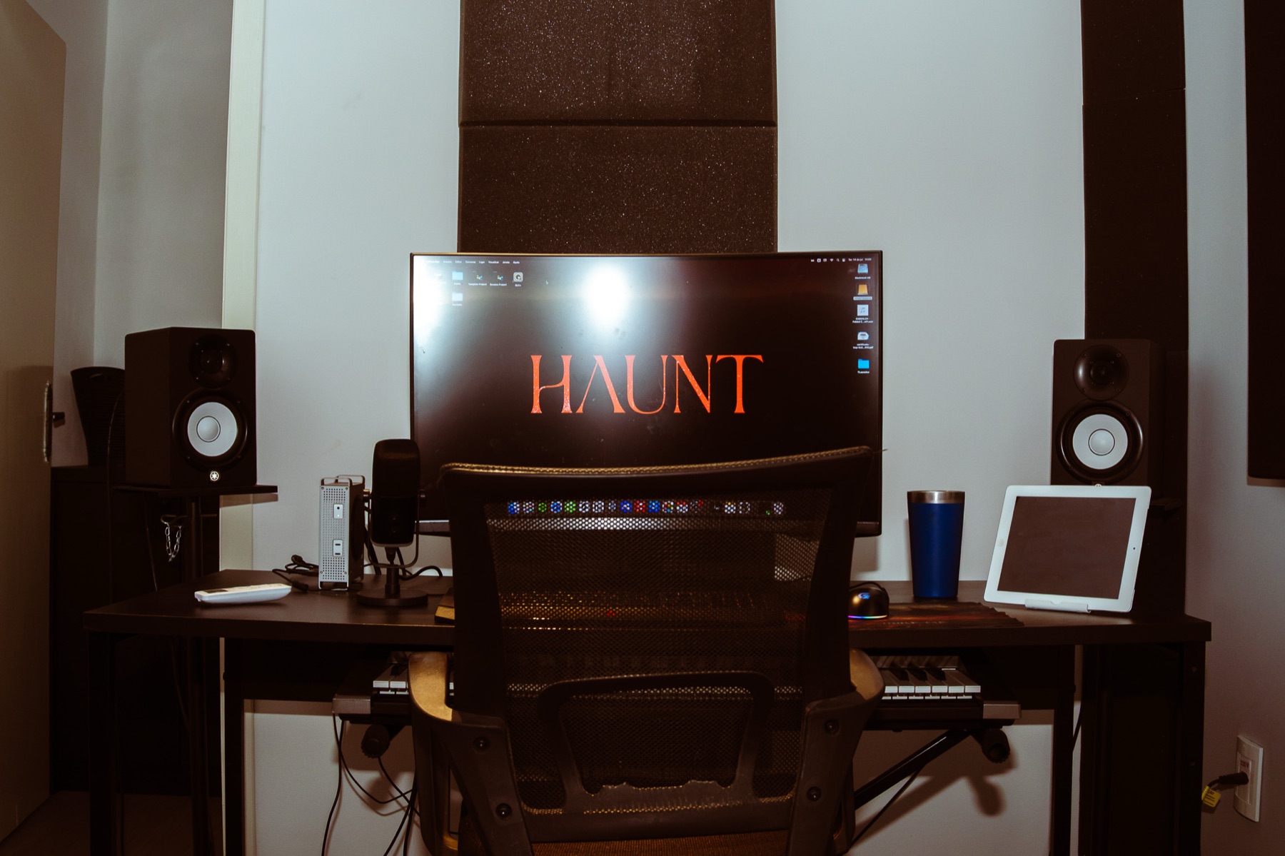 Estação de pós-produção vazia, com monitores de áudio e a marca HAUNT na tela