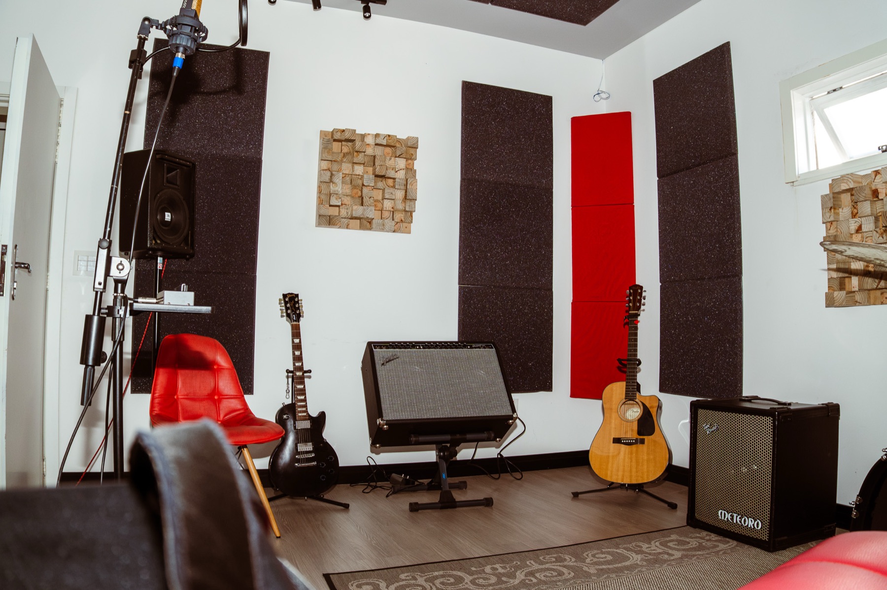 Sala de gravação tratada acusticamente, com guitarra, violão, amplificadores e microfone montado